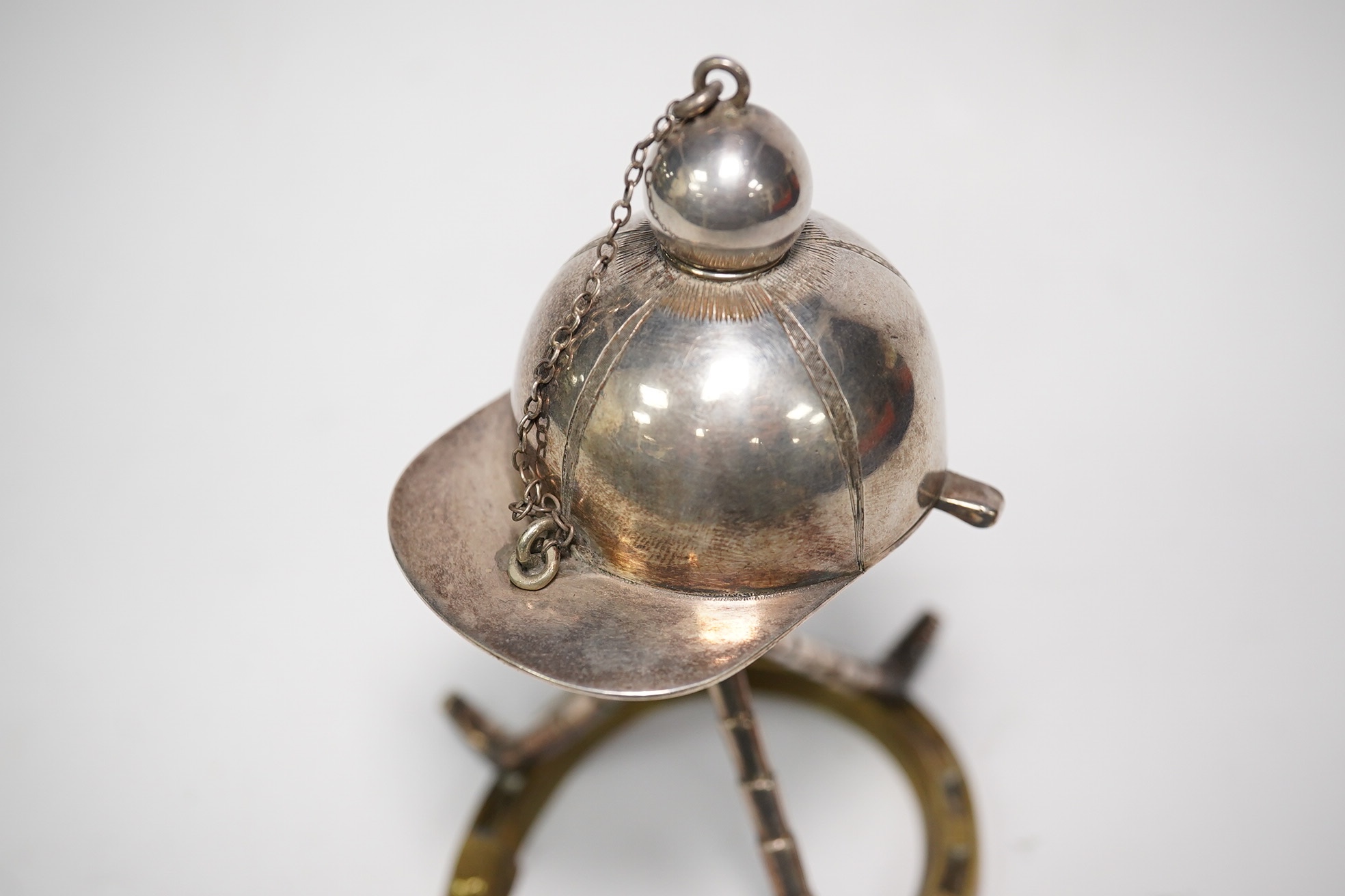 A late Victorian 'equestrian theme' silver plated novelty club lighter, modelled with a riding hat, crops and a horseshoe, 11.7cm. Condition - good
